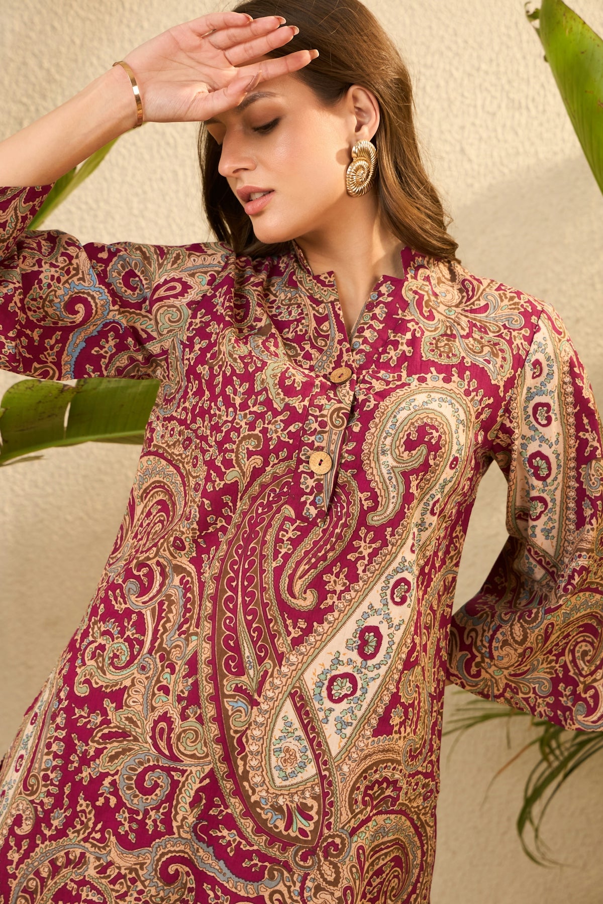 Woman in a patterned maroon dress with bell sleeves.