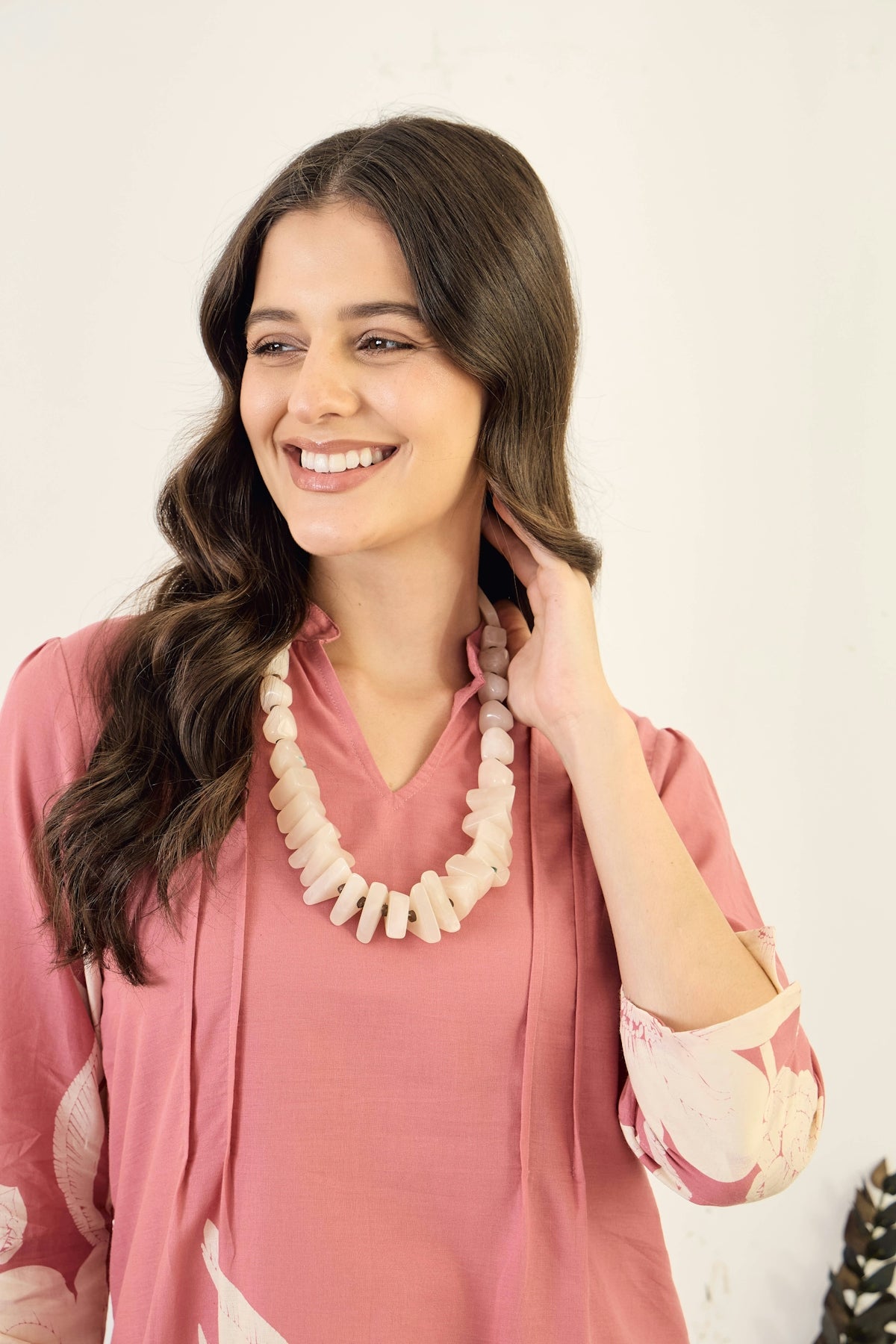 Woman wearing a pink dress and a beaded necklace