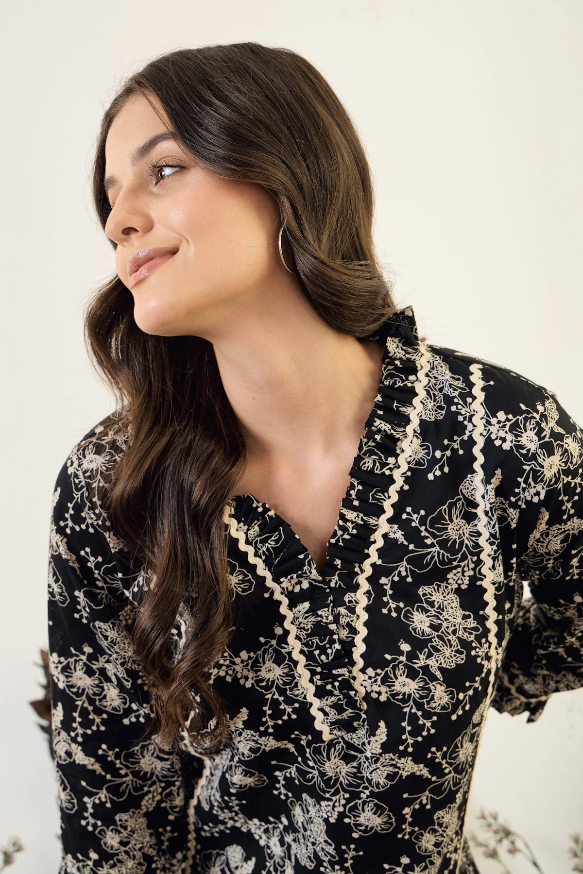A woman wearing a black floral embroidered top.