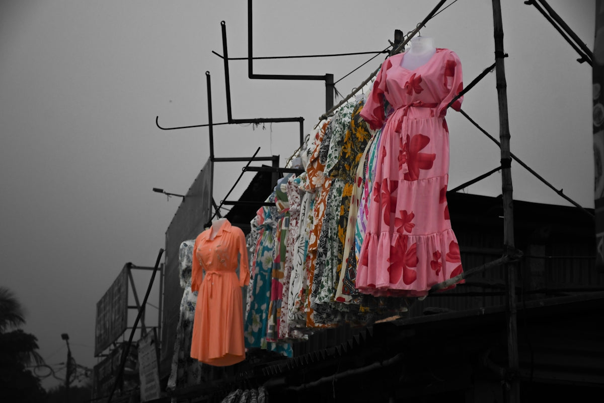 Dresses displayed on hangers outside a shop.